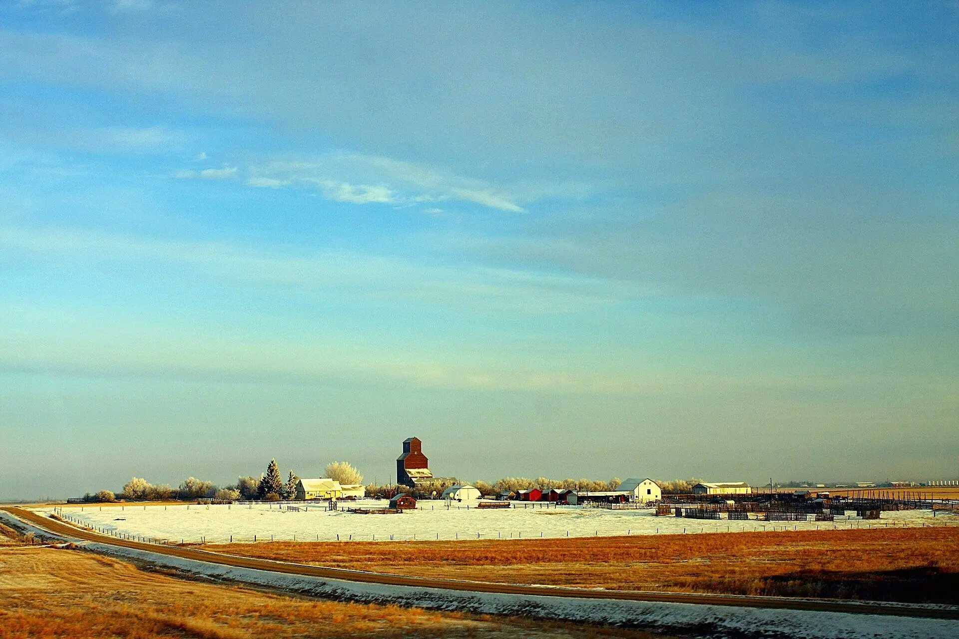 Village and grain elevator across snowy prairie