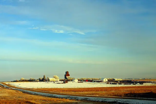Village and grain elevator across snowy prairie